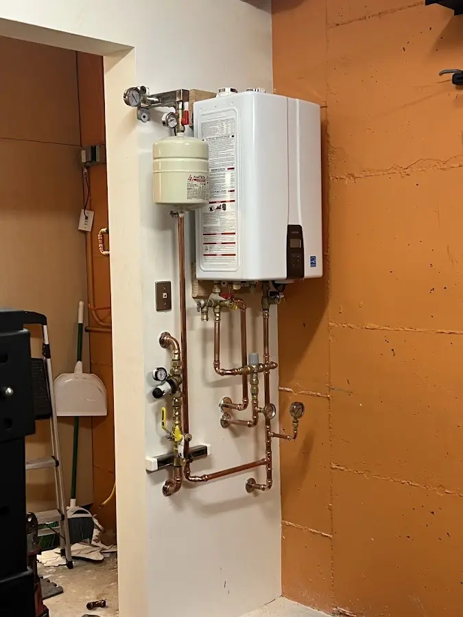 Plumbing technician inspecting water heater connections in Lackland AFB